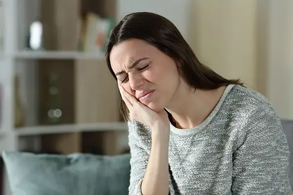 Woman holding her jaw in pain from TMJ that can be treated at Capitol Square Dental 