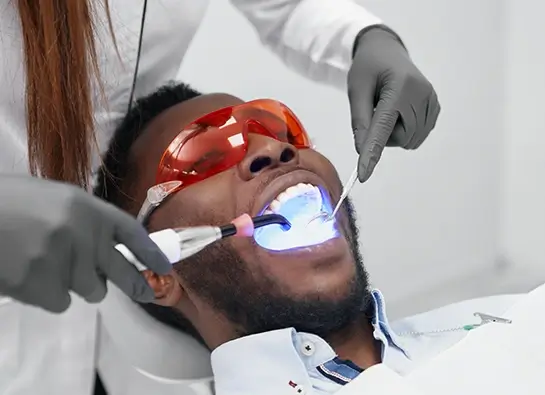 Man with his mouth open receiving a laser dentistry treatment