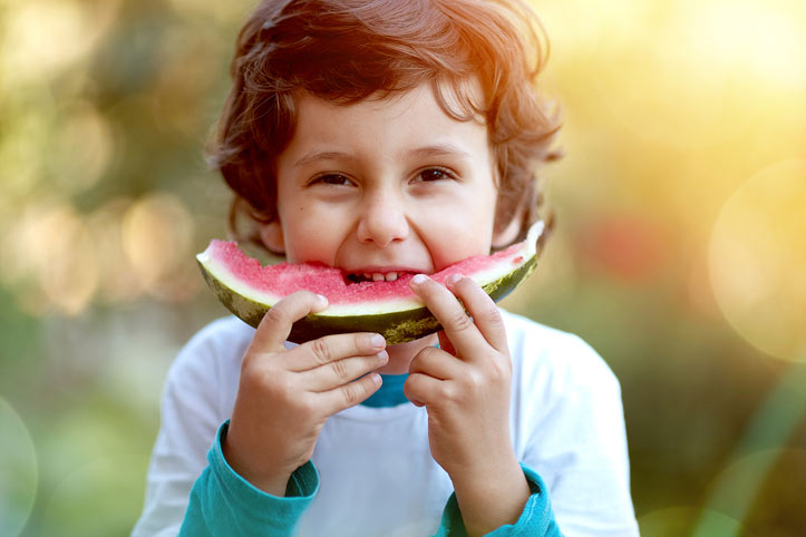 Little boy eating a large piece of watermelon